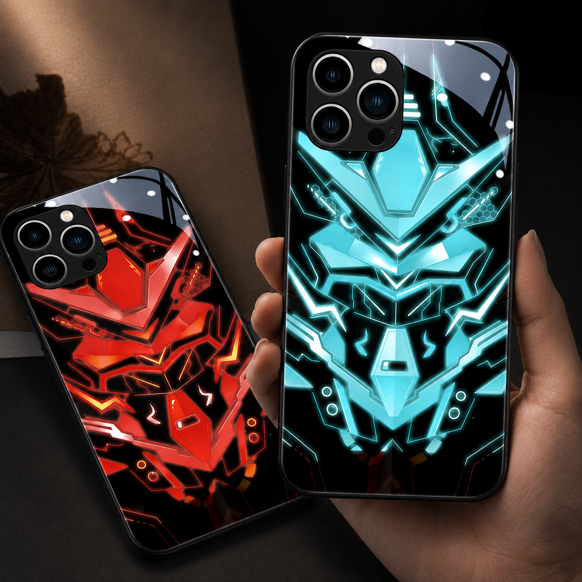 Hands hold orange and pale turquoise robotic-face cases side by side against a dark background.