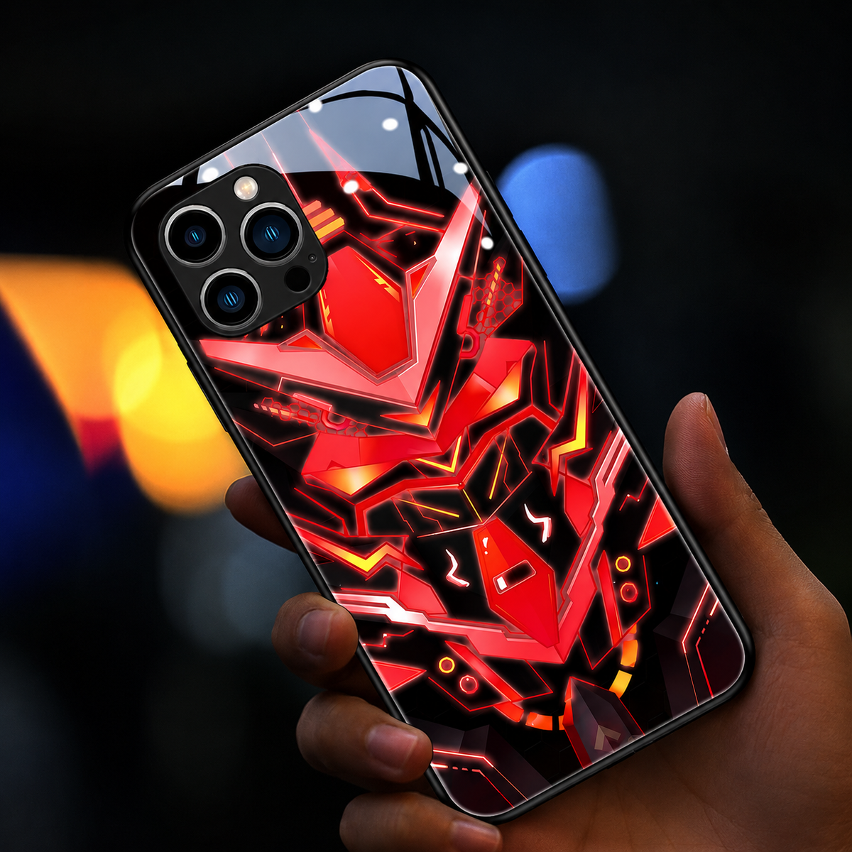 A hand holds a glossy black case decorated with an orange-red angular robotic face against blurred colored lights.