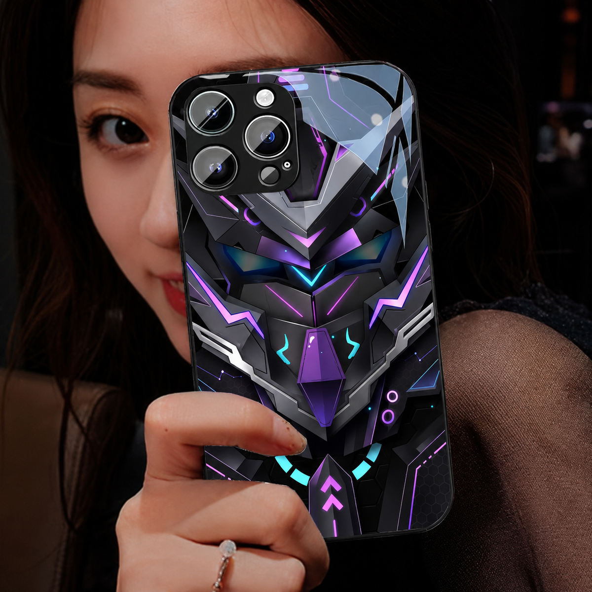 A woman holds a glossy case near her face, showing a silver-and-purple angular robotic mask on the back.
