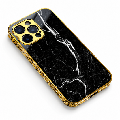 A black marble-pattern phone case lies diagonally against white. Fine white veins cross its back, framed by ornate gold-colored edges and a matching three-lens camera surround.