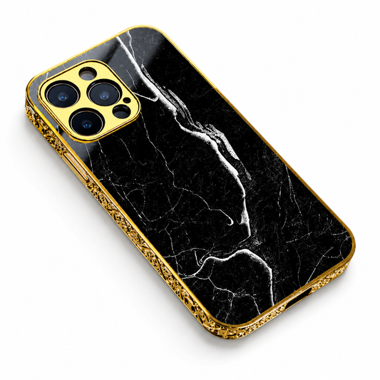 A black marble-pattern phone case lies diagonally against white. Fine white veins cross its back, framed by ornate gold-colored edges and a matching three-lens camera surround.
