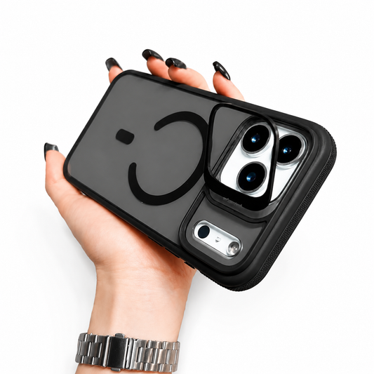 Hand with black nail polish and a silver watch holds a smoky transparent black case horizontally. The back has a broken circular magnetic ring and a rectangular metal-looking camera frame.