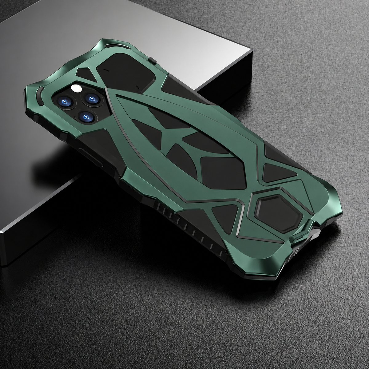 A green-and-black armor-style case rests across a dark block, with raised geometric rear sections and angular corners.