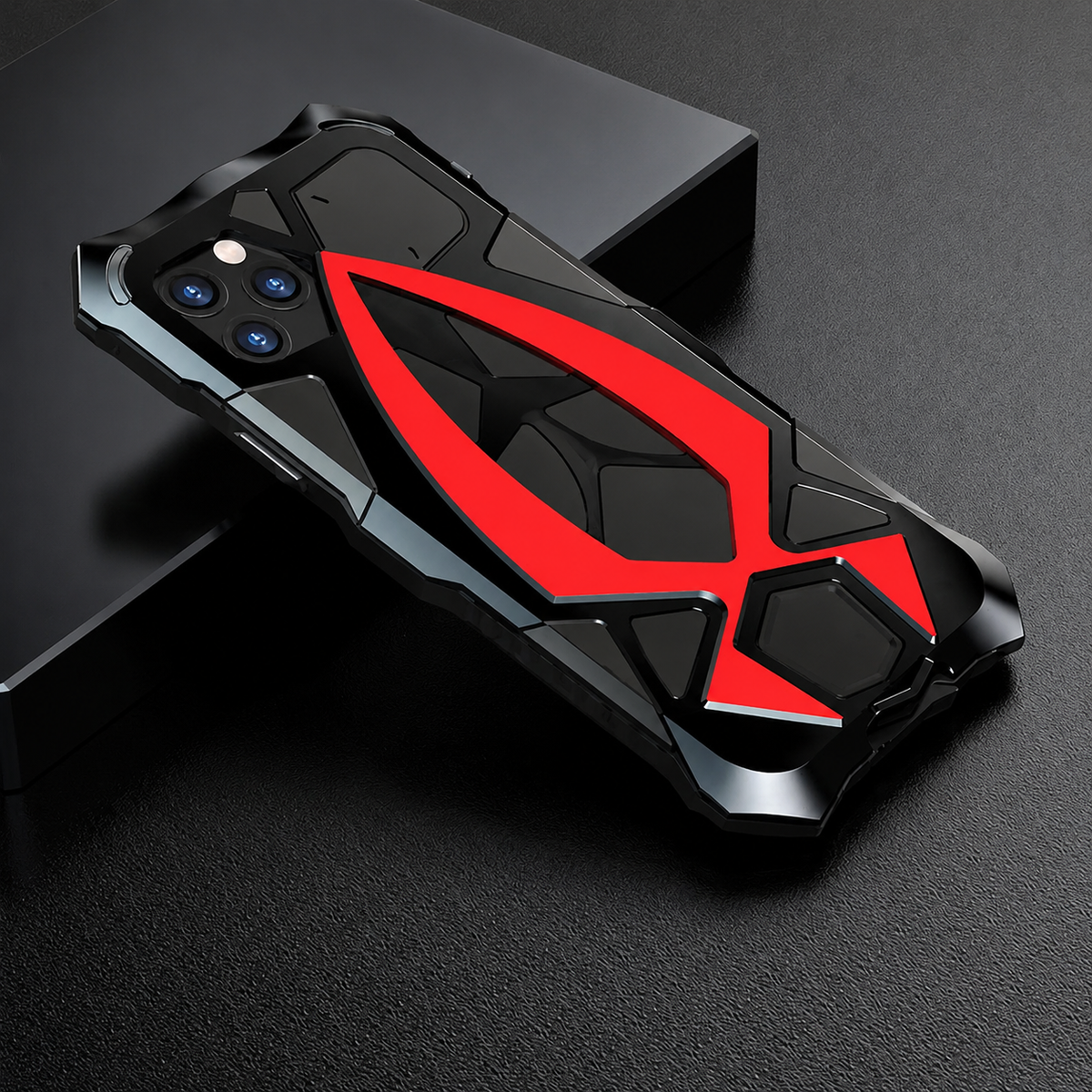 A black armor-style case with a bright red central angular accent lies on a dark block.