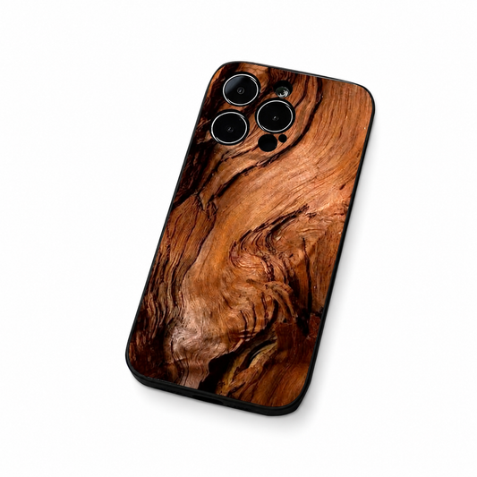 A phone case with a warm brown wood-grain design lies diagonally against white. Sweeping dark lines and knots cover its back, with separate circular camera openings and a slim black edge.