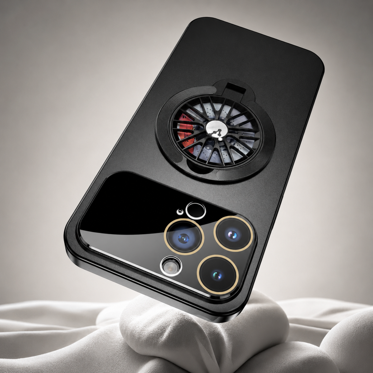 A black case rests diagonally against white folded fabric, showing its glossy camera panel and spoke-patterned rear ring.