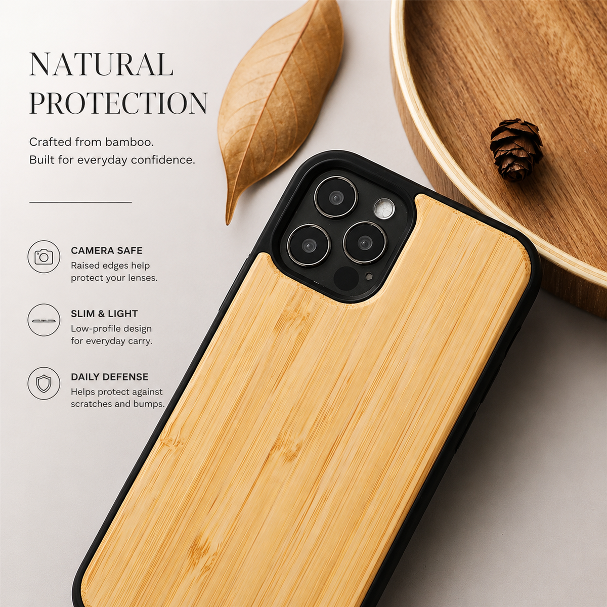 A close-up shows a golden wood-backed phone case lying diagonally on a pale surface beside a dry tan leaf and part of a wooden tray containing a small cone. Three cameras occupy the black surround at the upper left. Text headed 'Natural Protection' identifies bamboo and lists camera safety, slim design, and daily protection.