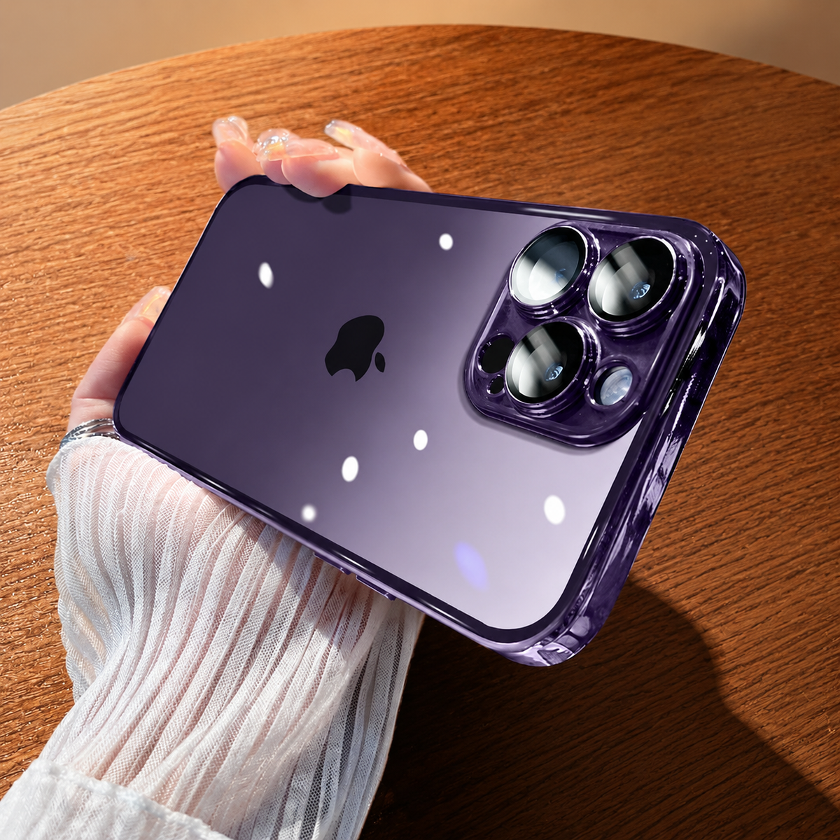 Hand holds a clear purple-edged case horizontally above a wooden table, showing the phone logo, raised camera surrounds, and bright light reflections.