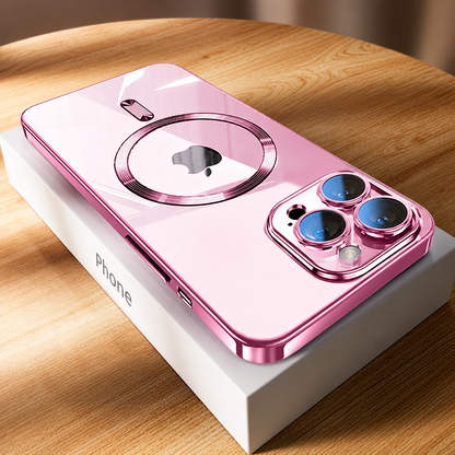 A pink-edged phone lies diagonally across a white box on a wooden tabletop. Its pale pink reflective back has a metallic-looking circular ring framing the phone logo and a short bar above. Three blue-reflecting camera lenses sit in a pink surround at the nearest corner. Sunlight casts bright bands across the wood.