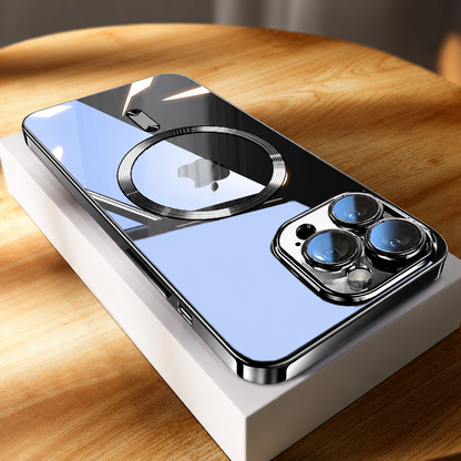 A black-edged phone rests diagonally on a white box on a sunlit wooden tabletop. Strong black, white, and blue reflections cross the glossy back around a metallic-looking circular ring and phone logo. Three camera lenses sit inside a reflective surround at the nearest corner, while the case edges catch bright highlights.
