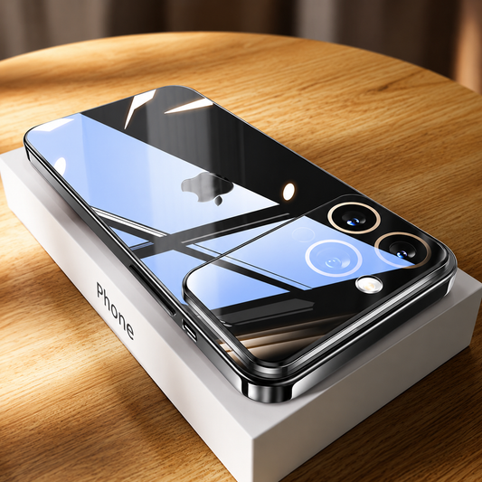 A glossy black-edged phone case lies face down on a white box on a sunlit wooden table. Window reflections cross its back and black camera panel, with gold-colored rings around two lenses.