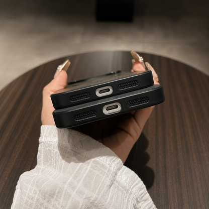 Bottom-edge view of two stacked phones in black cases, with centered charging-port openings and speaker grilles on either side.