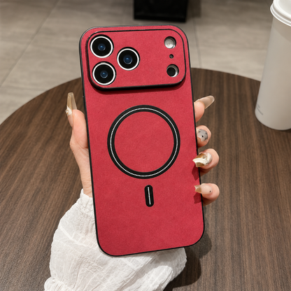 A hand holds a red leather-look phone case above a wooden table, with a matching camera guard, black border and black circular ring and bar.
