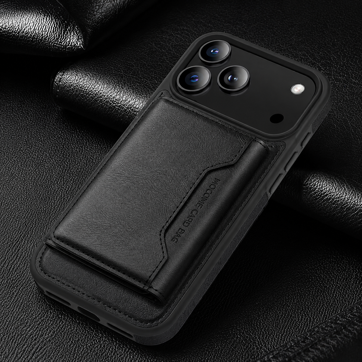 A black wallet case lies diagonally on textured black fabric, with a closed stitched flap below its broad camera panel.
