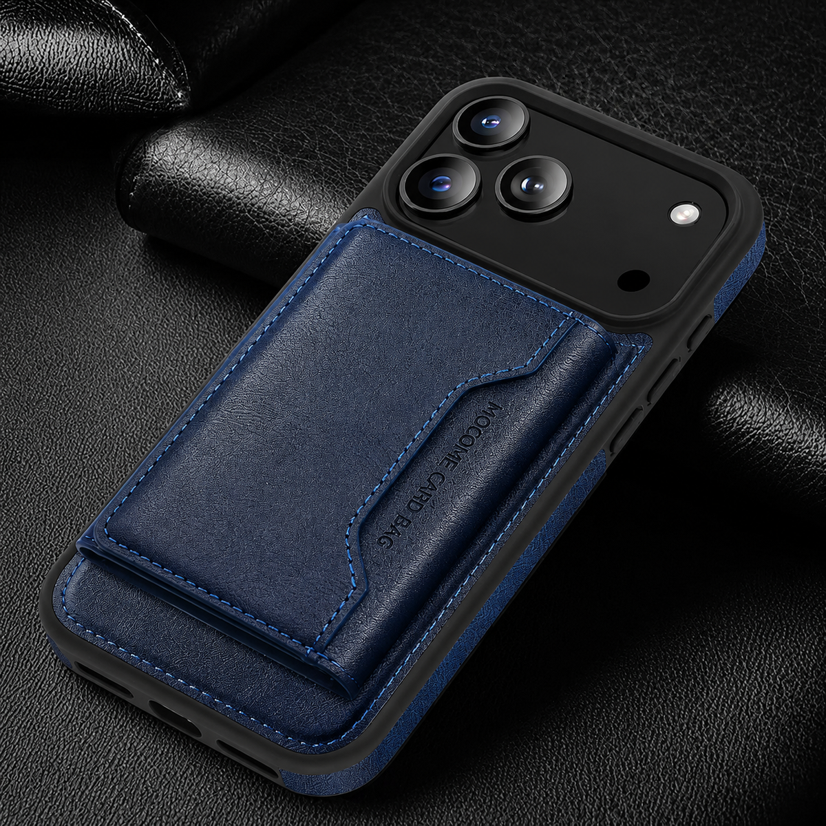 A navy wallet case lies diagonally on black textured fabric, showing its stitched rear flap and black camera panel.