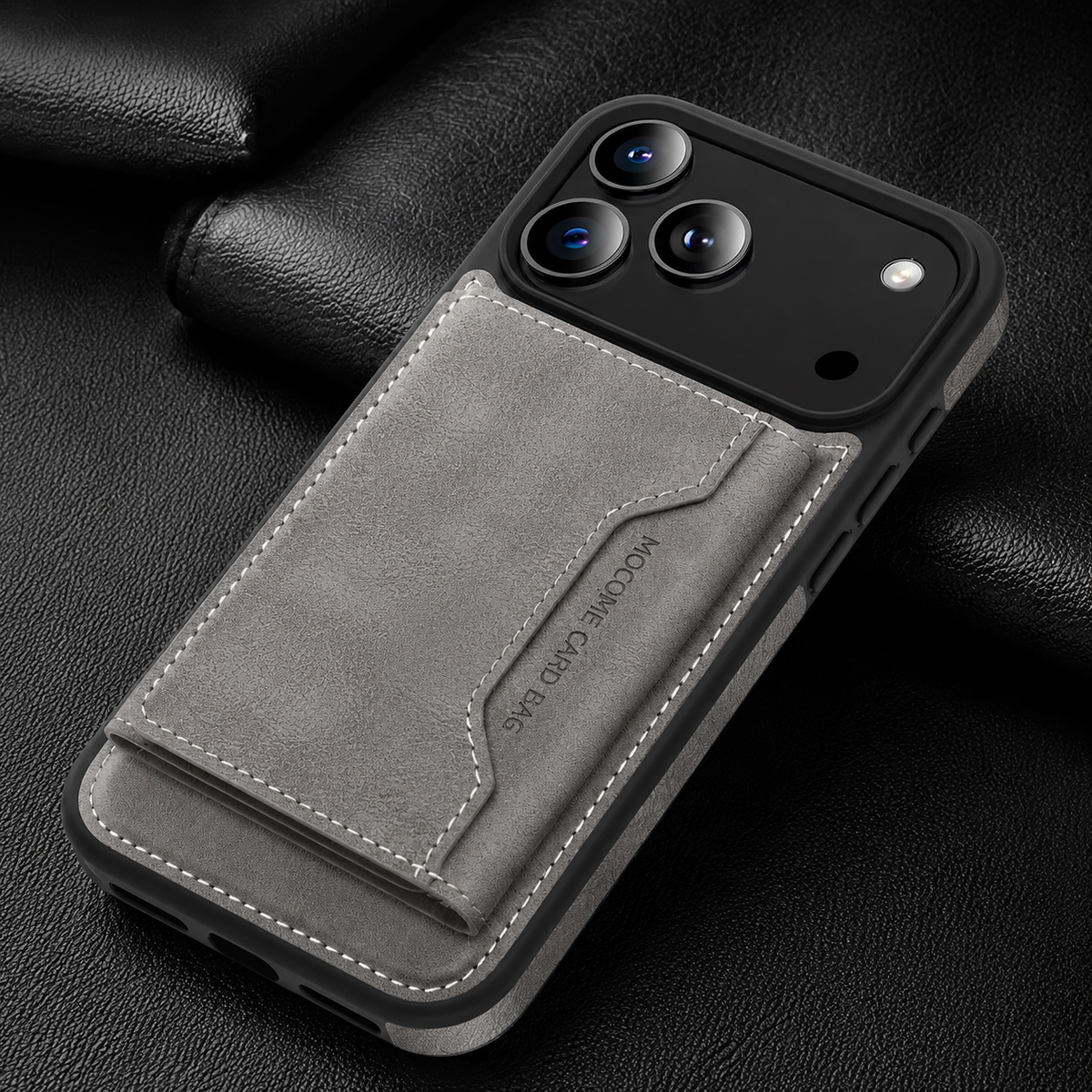 A gray wallet case lies diagonally on black fabric, showing its closed stitched rear flap.