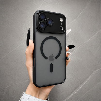 A hand holds a smoky gray frosted phone case upright against gray stone. Its black ring surrounds the visible Apple logo, with a short bar below and broad three-camera panel above.
