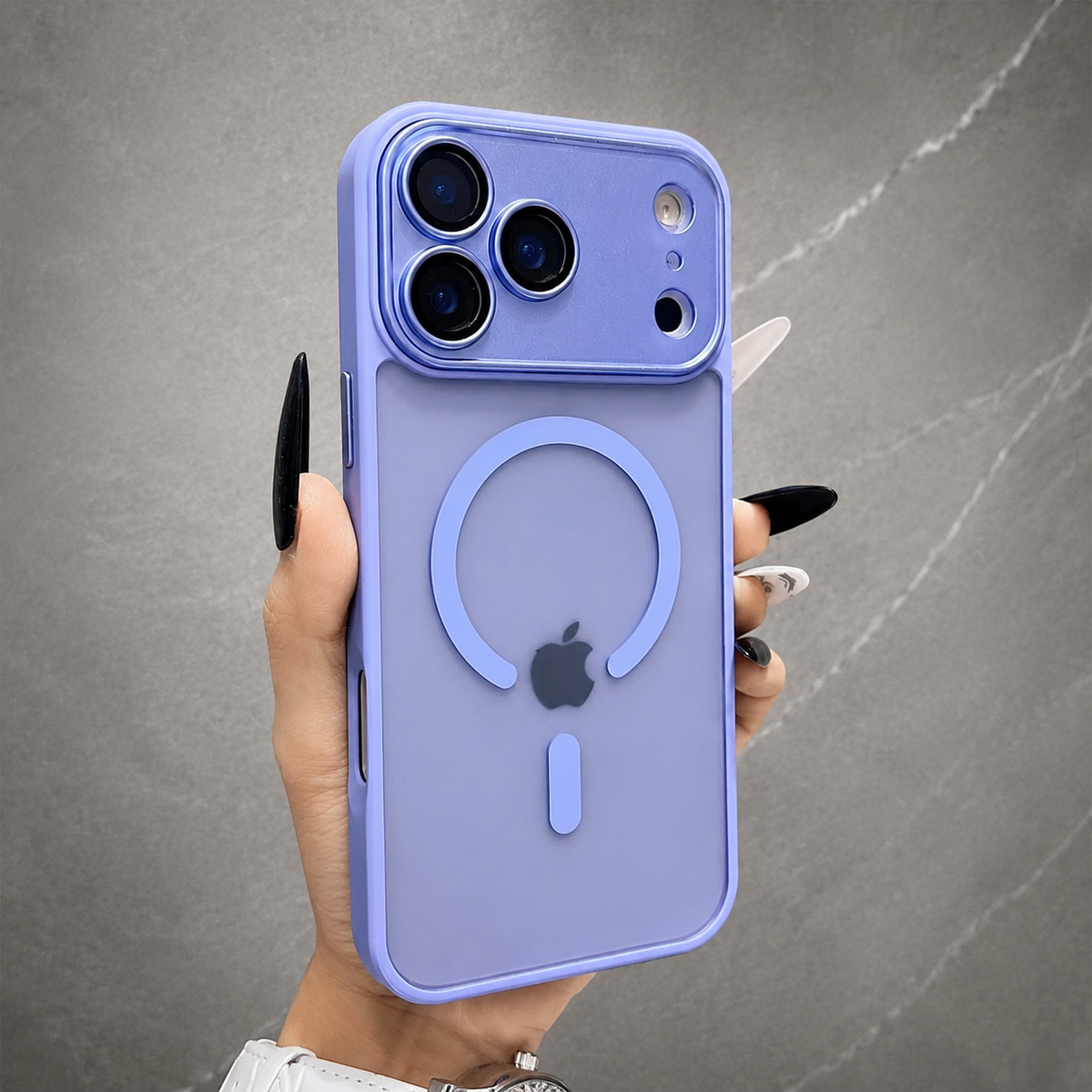 A hand holds a lavender frosted phone case upright against gray stone, showing a matching open circular rear ring, short bar and broad camera panel.