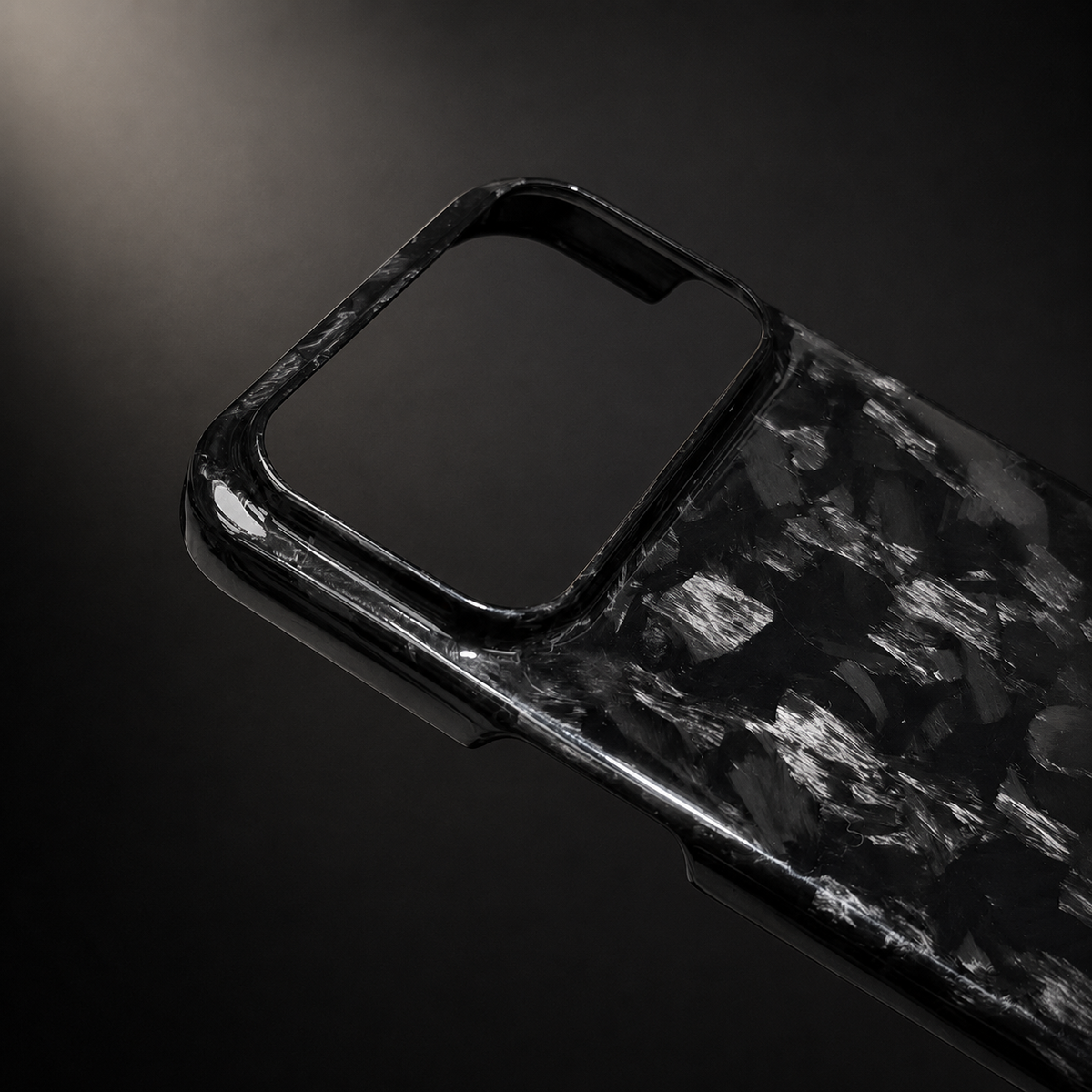 A close-up shows glossy black and silver-gray shard-like patches around the raised rim of a wide rectangular camera opening against a dark background.