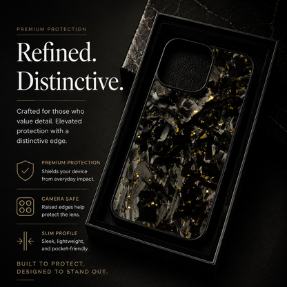 A black case with gray fragments and gold flecks rests in a rectangular black tray on dark stone. Its large rounded square camera opening is visible beside promotional text.