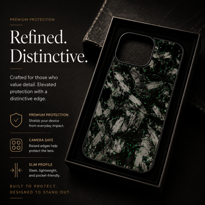 A glossy black case with large silver-gray fragments rests in a black presentation tray. Its empty rounded square camera opening has a raised black border. Text advertises everyday protection, camera-safe edges and a slim profile.