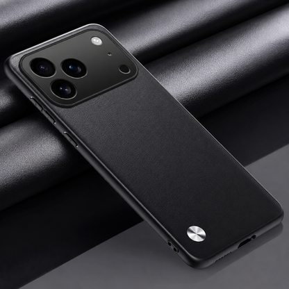 Black textured phone case lying diagonally on dark folded fabric, with a wide camera opening and small silver circular accent at the lower left.