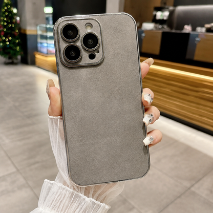 Hand holds a gray suede-look case upright in a café, showing its mottled back, silver-colored edge, and individual camera lens surrounds.