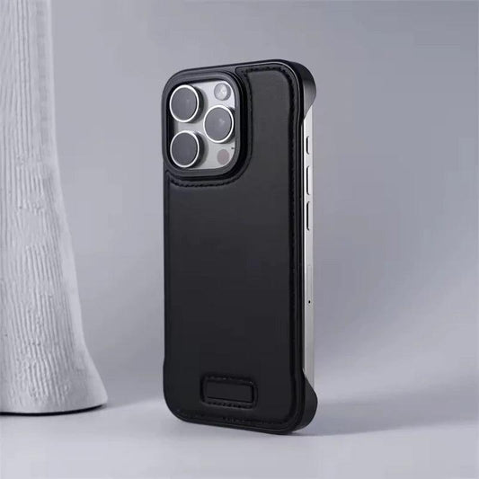 A black leather-look phone case stands beside a white textured vase on a gray surface. Stitching outlines its back and camera opening, with exposed silver-colored sides and a small rectangular plaque near the bottom.