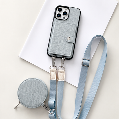 A pale blue textured wallet phone case rests on an angled white sheet beside a matching round zippered pouch and long adjustable strap. A stitched card flap with a silver-colored snap covers the rear. Metal clips connect the strap to two loops on the phone's lower edge, with pale fabric sections near the clips.