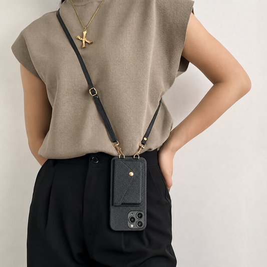 A person in a taupe sleeveless top and black trousers wears a black wallet phone case on a narrow adjustable crossbody strap, with the case hanging at the hip.