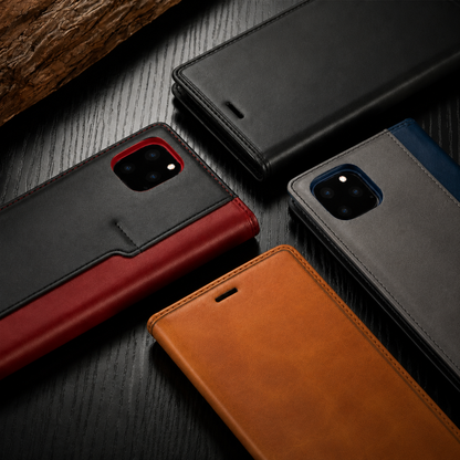 Four wallet cases lie diagonally on dark wood in black, red with black trim, blue with gray trim and tan. Front and rear panels show stitching, earpiece slots and camera openings.