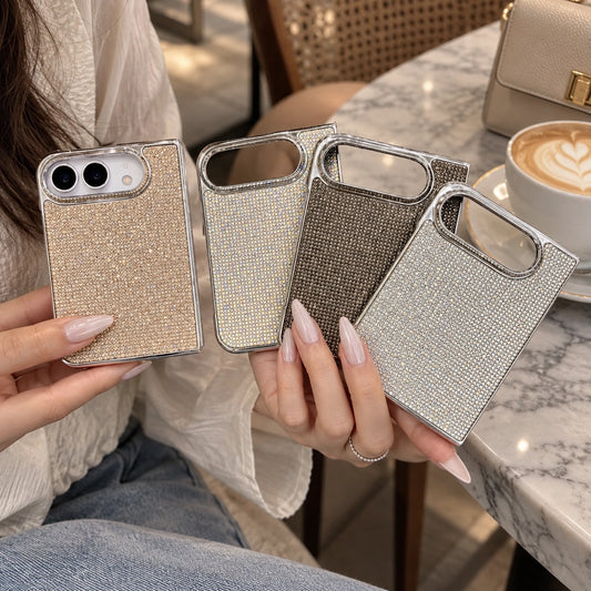 A person holds four rhinestone-embellished phone cases in different metallic colors: gold, champagne, bronze, and silver. The background shows a cozy cafe setting with a marble table, a cup of latte, and a leather handbag.
